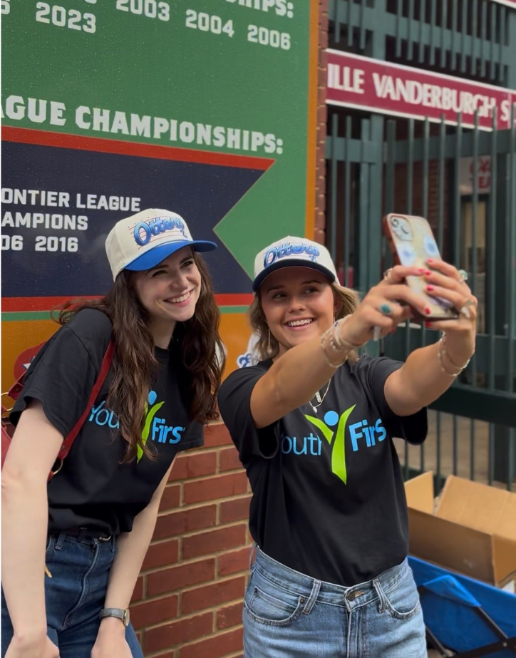 Members of the Youth First staff selfie with their Heritage Evansville Otters baseball cap at Heritage & Youth First Night at the Otters.